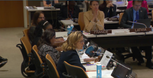 Captures a table of 6 distinguished experts, speakers and states representatives at the United Nations Headquarters, France and Latvia are facing the camera with four women to right whos faces are half seen, panel is titled “Combatting Trafficking for the Purposes of Sexual Exploitation by Armed and Terrorist Groups: Closing Information Gaps and Strengthening Cooperation to Promote Accountability for Survivors.”